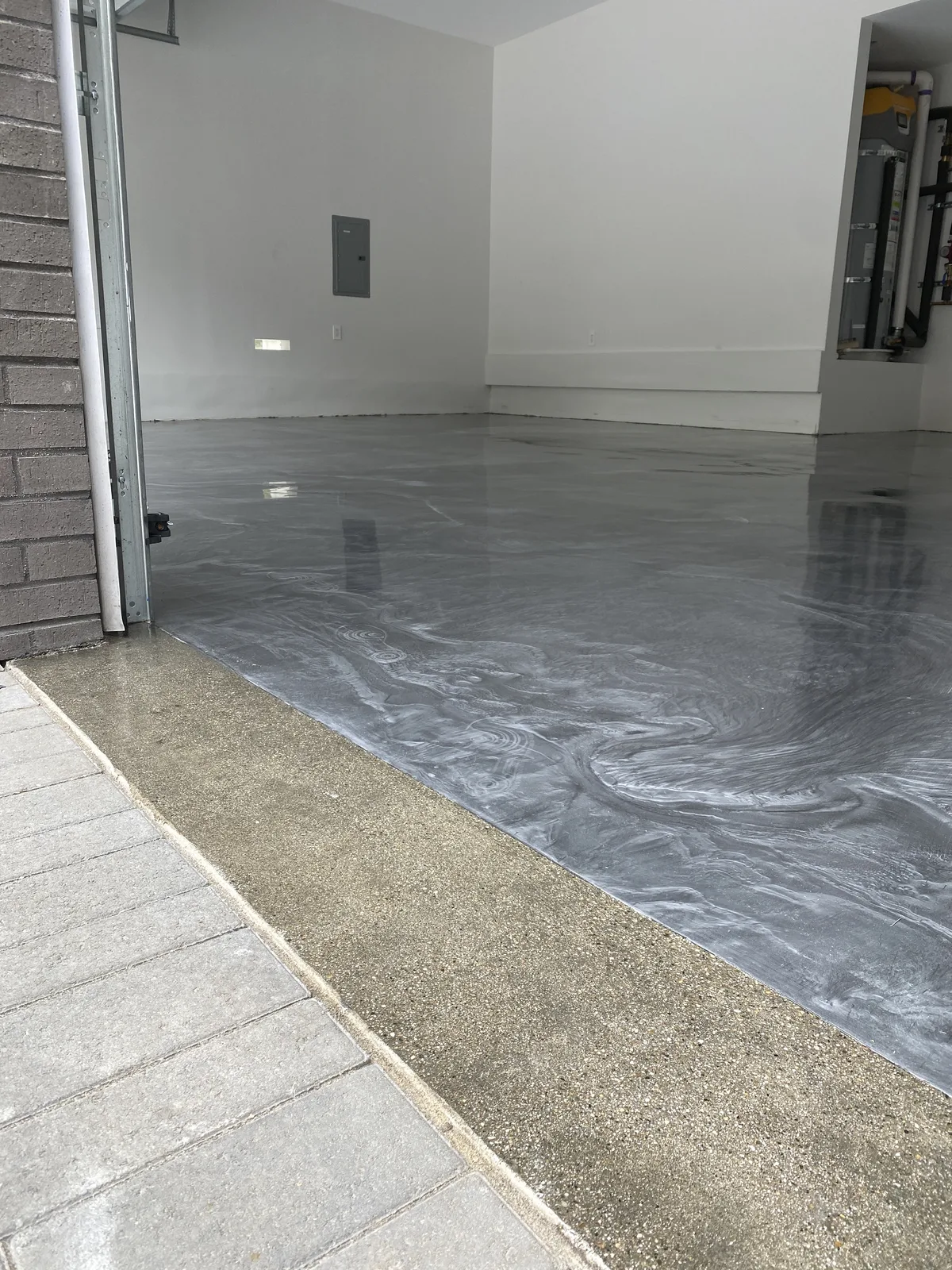 Swirled silver metallic epoxy garage floor at the driveway edge