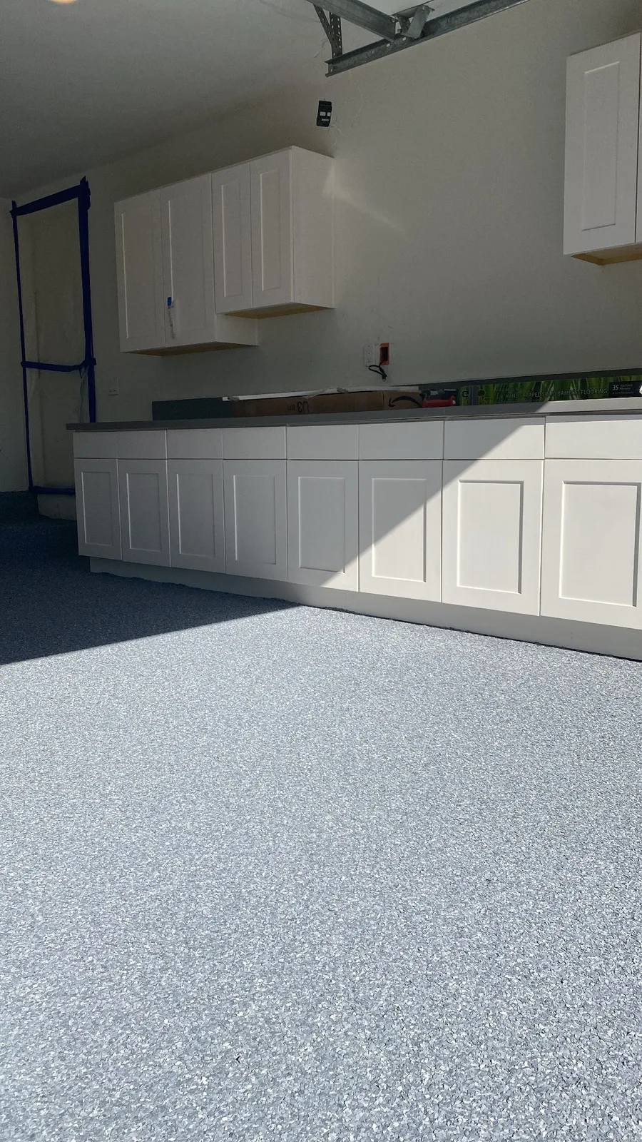 Gray flake epoxy garage floor beside built-in storage cabinets