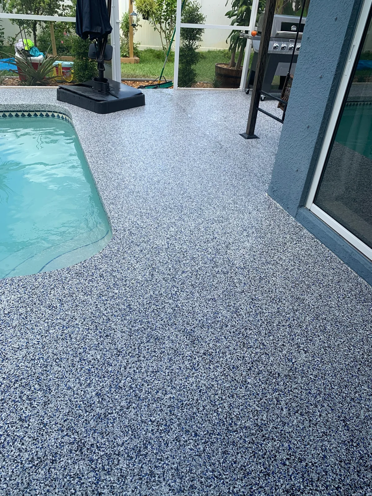 Blue-toned flake epoxy deck beside a pool